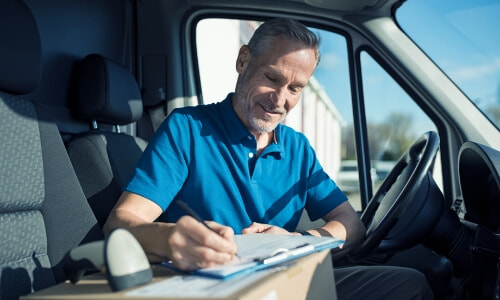a man sitting in a vehicle writing on a clipboard