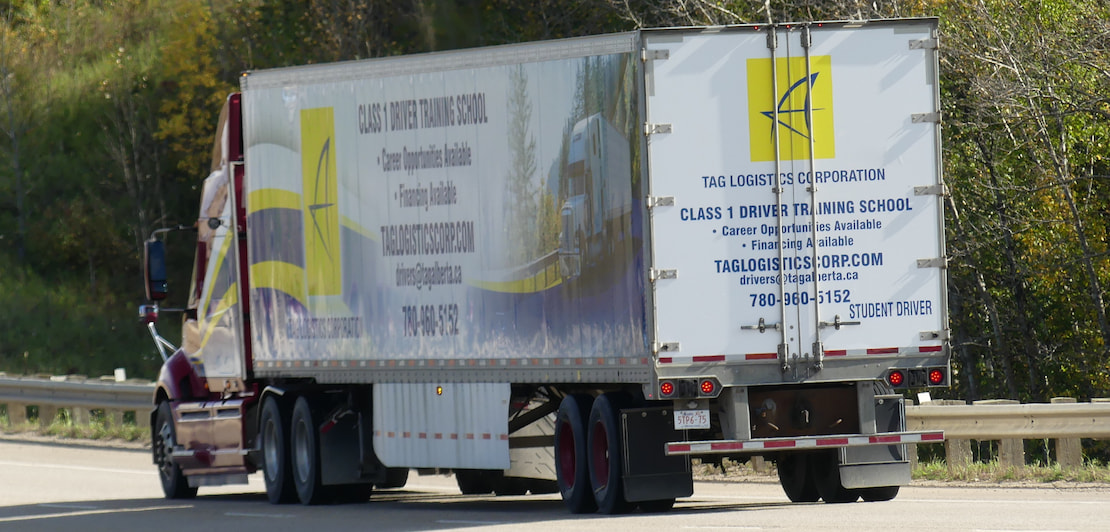 a red semi-truck with a trailer that says Tag Logistics Corporation and Class 1 Driver Training School